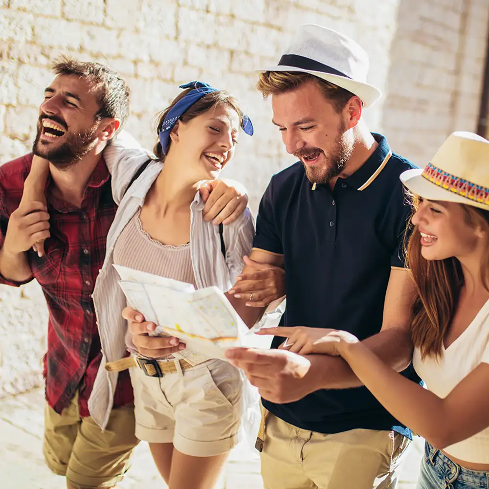 Turistas felices mostrando un mapa y riendo juntos al aire libre