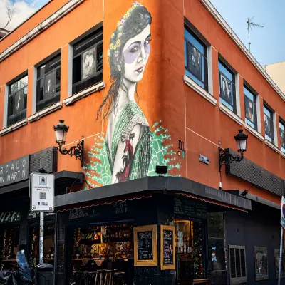 Mural de una mujer con vestido y peinado sobre fachada naranja de edificio.