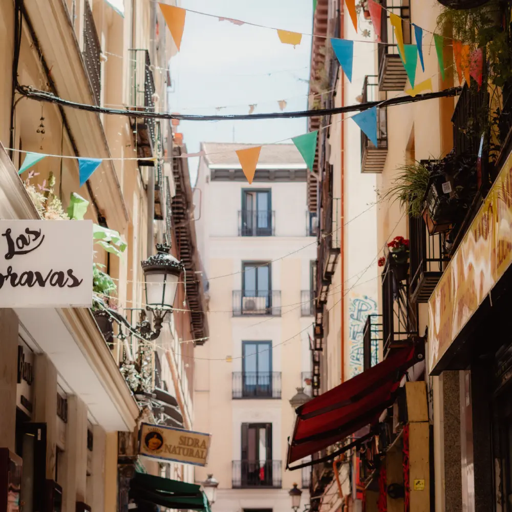 Calle estrecha con banderines de colores, balcones y faroles sobre el fondo