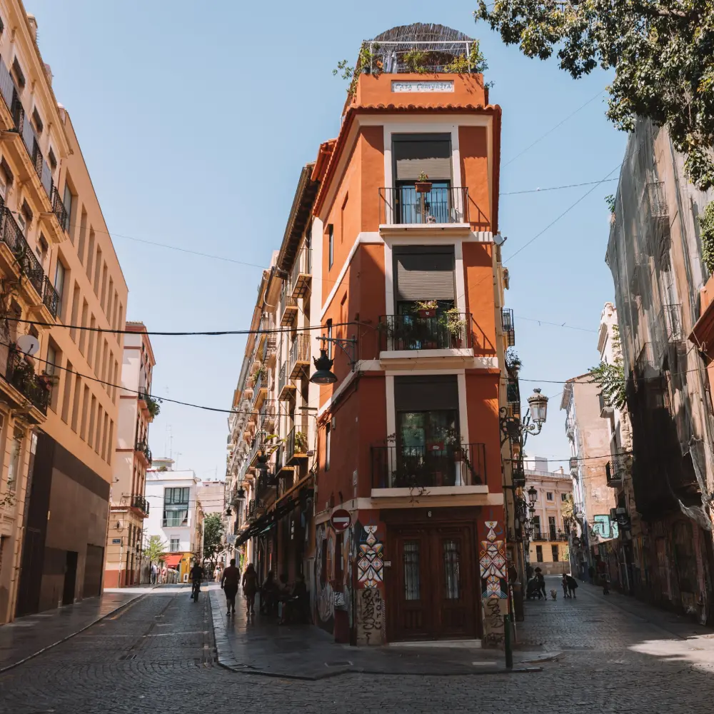 Calle estrecha con edificio naranja de balcones y l&aacute;mparas, cielo azul