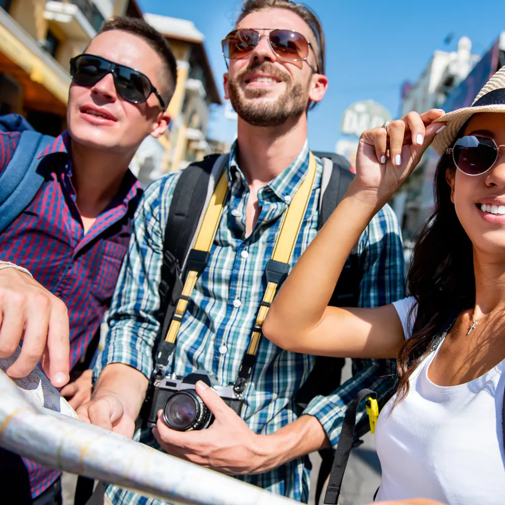 Turistas con gafas y mochilas en la calle, con c&aacute;mara y toma de selfie.