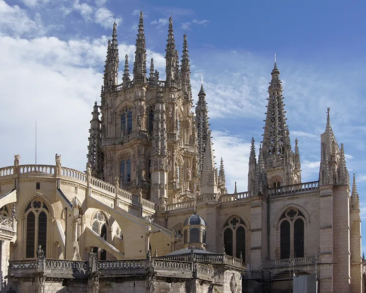 Catedral g&oacute;tica con agujas y torres bajo cielo azul, exterior.