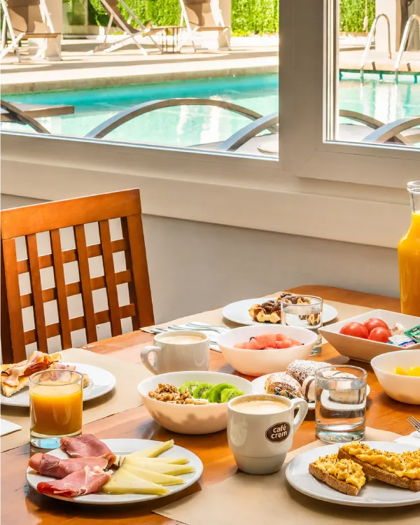 Desayuno en terraza: mesa con frutas, caf&eacute; y vista a la piscina