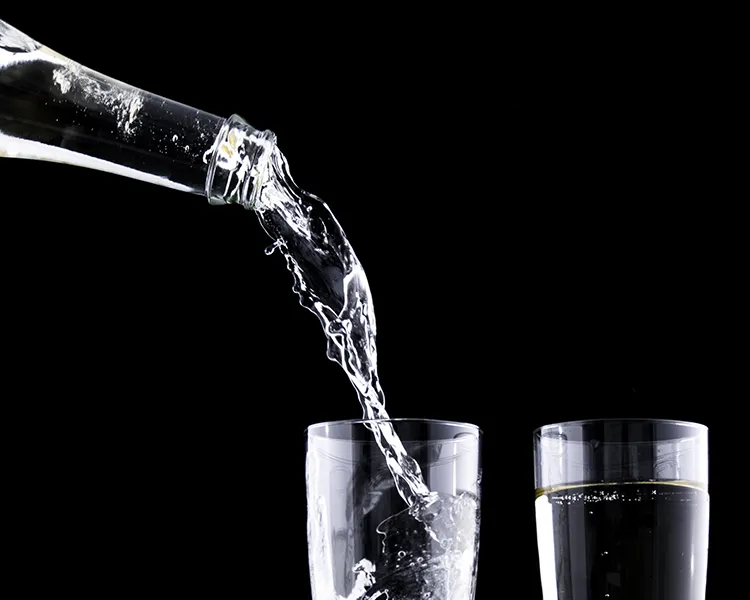 Chorro de agua cayendo en vasos de vidrio sobre fondo negro