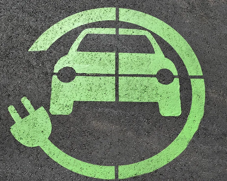 Icono de coche el&eacute;ctrico verde con flechas en c&iacute;rculo sobre asfalto gris.