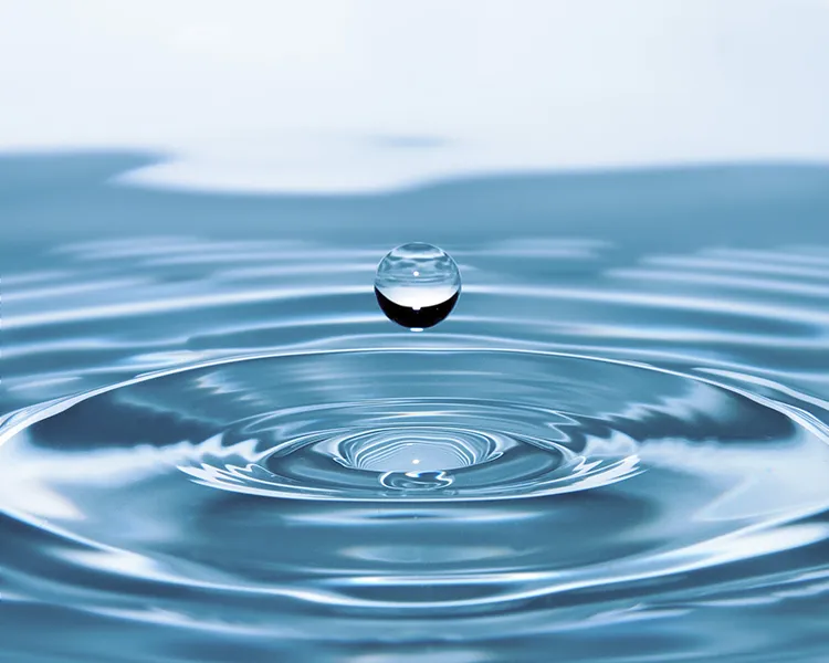 Gota de agua en el centro formando ondas sobre una superficie azul