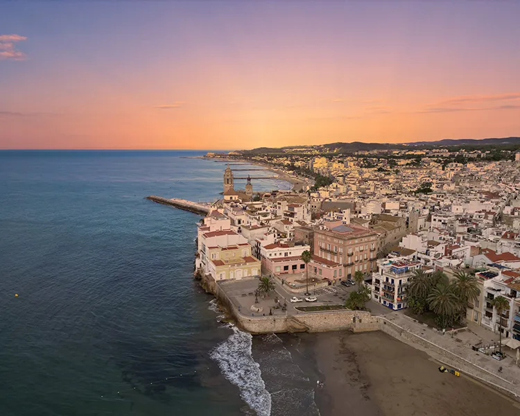 Atardecer sobre la costa con un pueblo blanco y un faro junto al mar