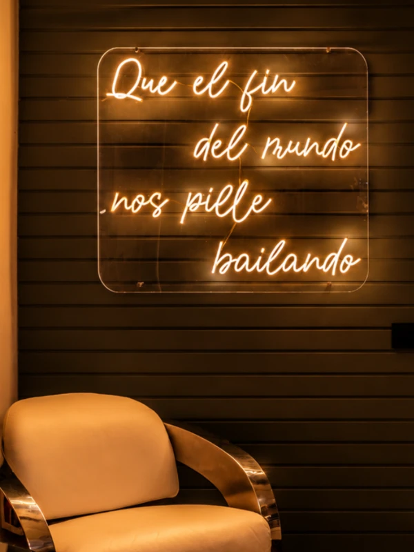 Ne&oacute;n con frase &ldquo;Que el fin del mundo nos pille bailando&rdquo; sobre pared