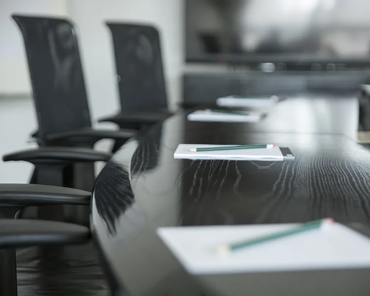Sala de oficina con sillas negras y carpeta sobre mesa de trabajo