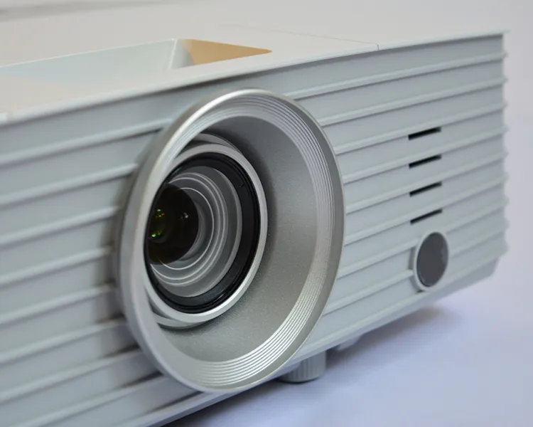 Proyector port&aacute;til con lente circular y carcasa gris sobre fondo claro