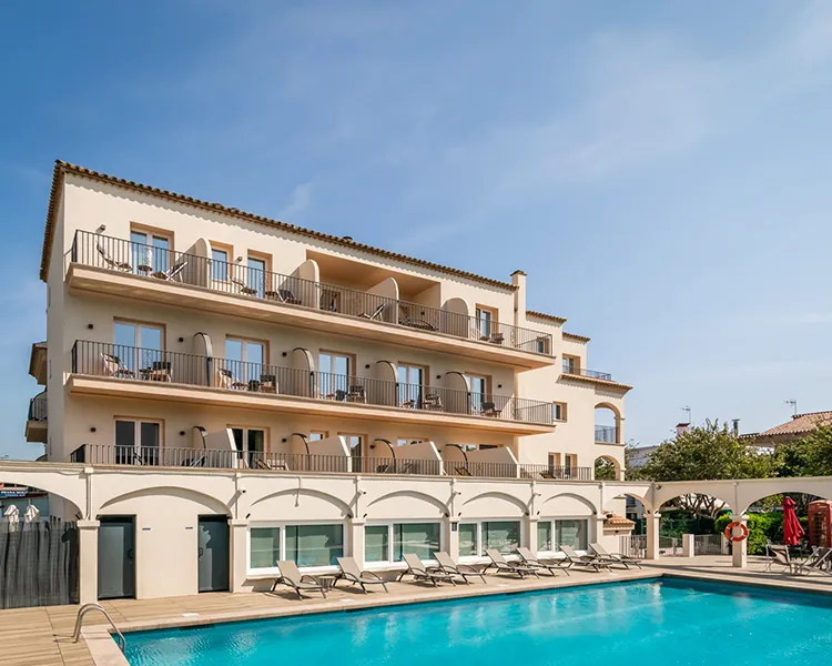 Hotel con piscina y balcones en fachada blanca bajo cielo despejado