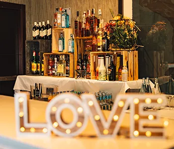 Mesa de bar con botellas y luces decorativas estilo &ldquo;LOVE&rdquo;