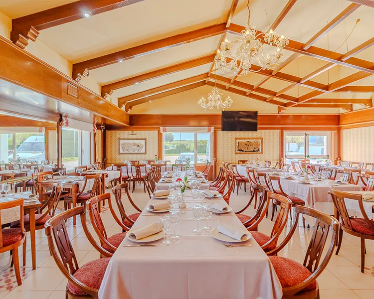 Comedor elegante con mesas servidas y l&aacute;mparas de ara&ntilde;a de cristal.