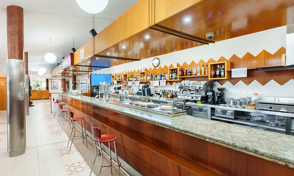 Bar con mostrador de m&aacute;rmol, utensilios y estanter&iacute;as de bebidas en interior