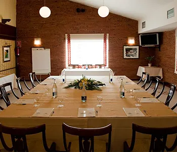 Sala de reuniones con mesa larga, sillas y luz sobre la mesa