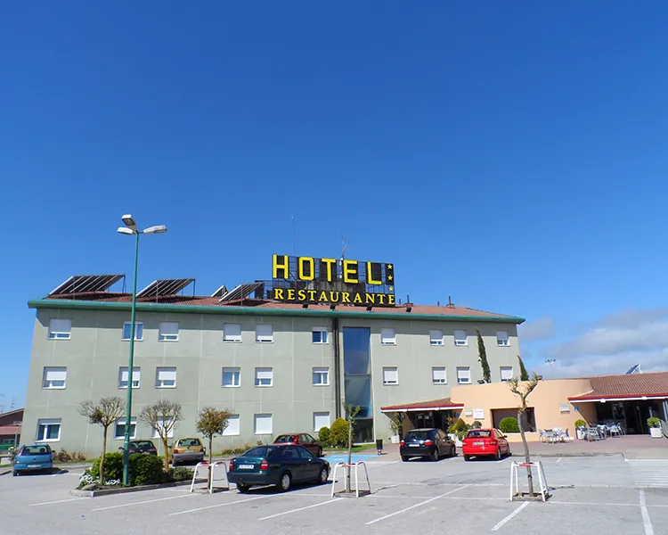 Hotel &ldquo;Restaurante&rdquo; en edificio con letrero amarillo, cielo azul.