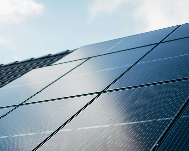 Placas solares azules en primer plano bajo el cielo nublado