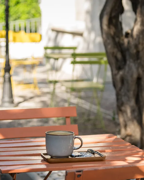 Taza de caf&eacute; sobre mesa de madera en terraza al aire libre
