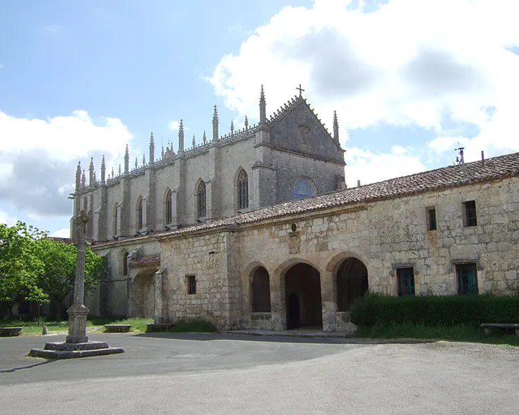 Iglesia de estilo g&oacute;tico con contrafuertes y torreones sobre patio.