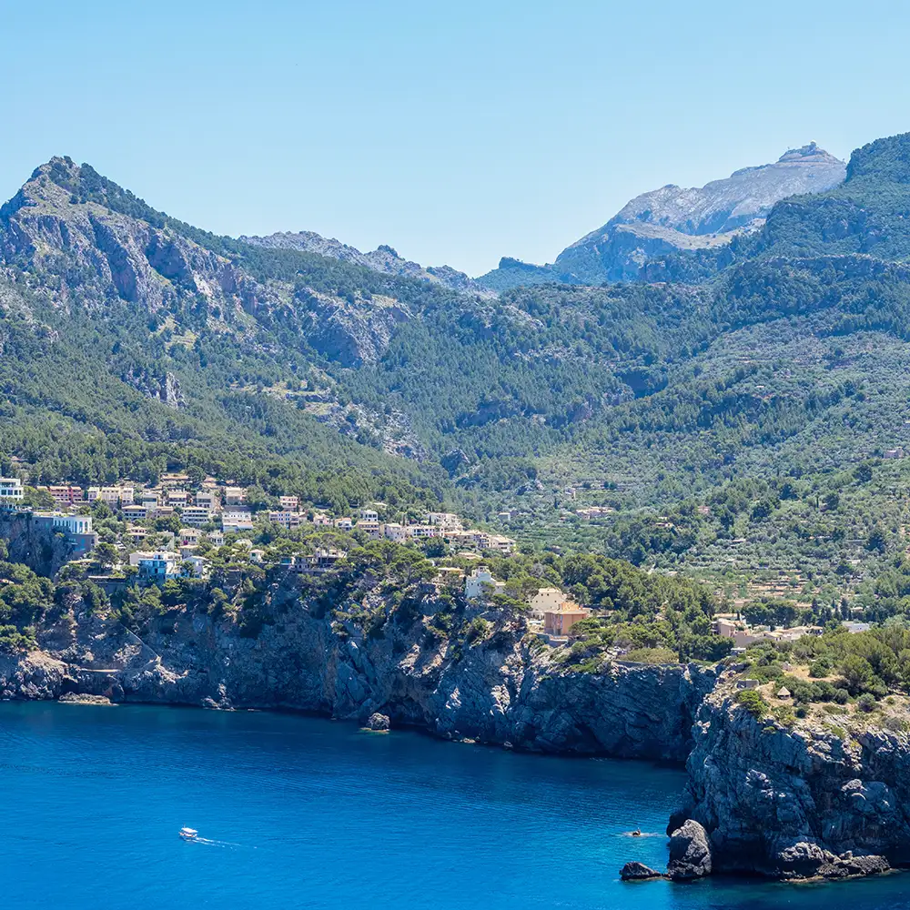 Bah&iacute;a mediterr&aacute;nea con monta&ntilde;as y casas junto al mar azul