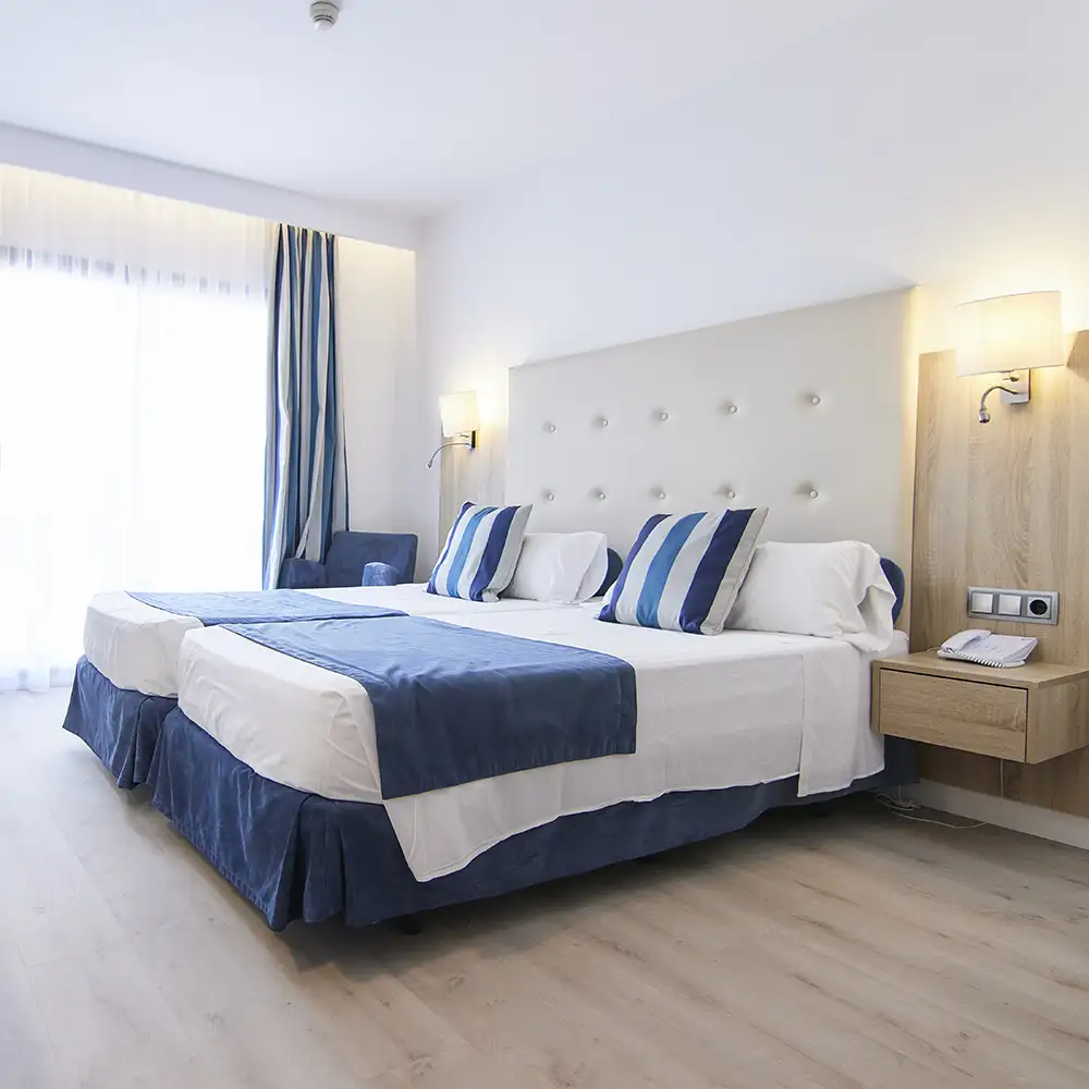 Habitaci&oacute;n de hotel moderna con cama doble y almohadas azules