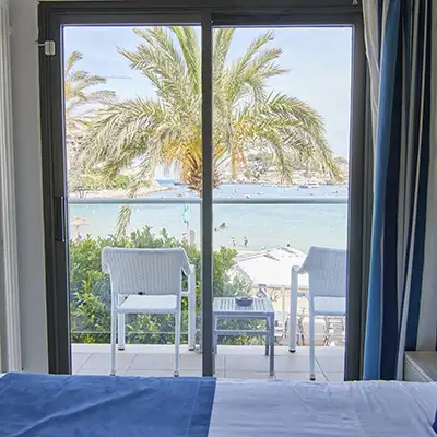 Terraza con dos sillas y vista al mar entre palmeras.
