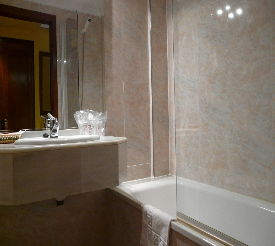 Ba&ntilde;o moderno con lavabo, ducha y cortina de ducha de vidrio abierta