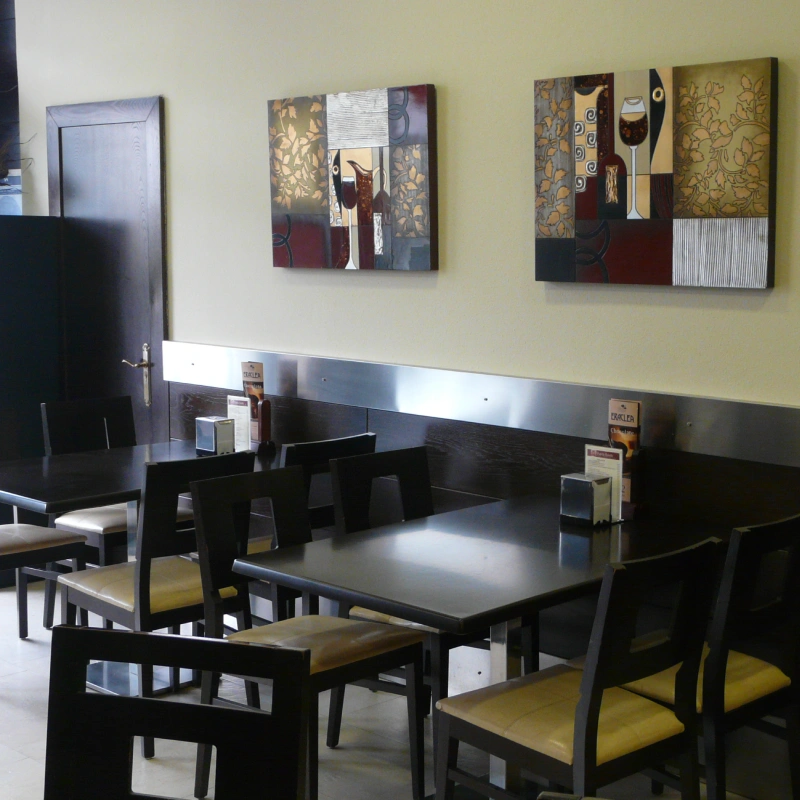 Sala con mesas negras y cuadros decorativos en la pared.