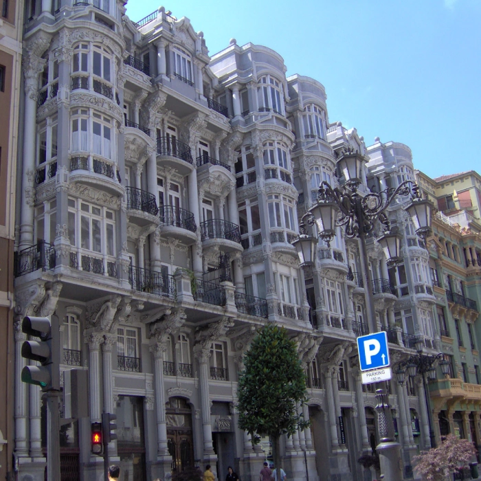 Fachada de edificio hist&oacute;rico con arcos y balcones, cielo azul.