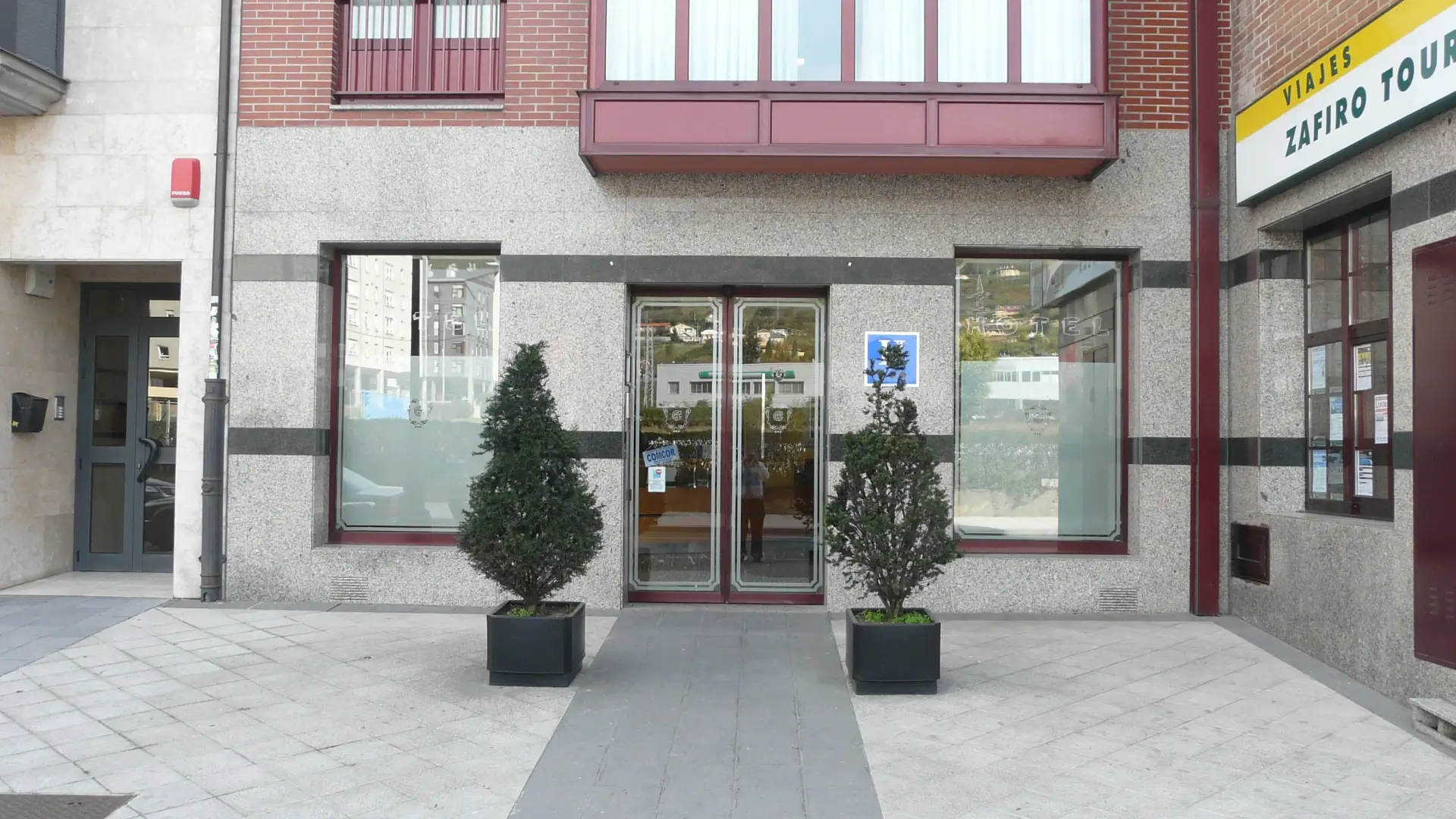 Entrada de edificio con puerta de vidrio y ventanas en ladrillo y piedra