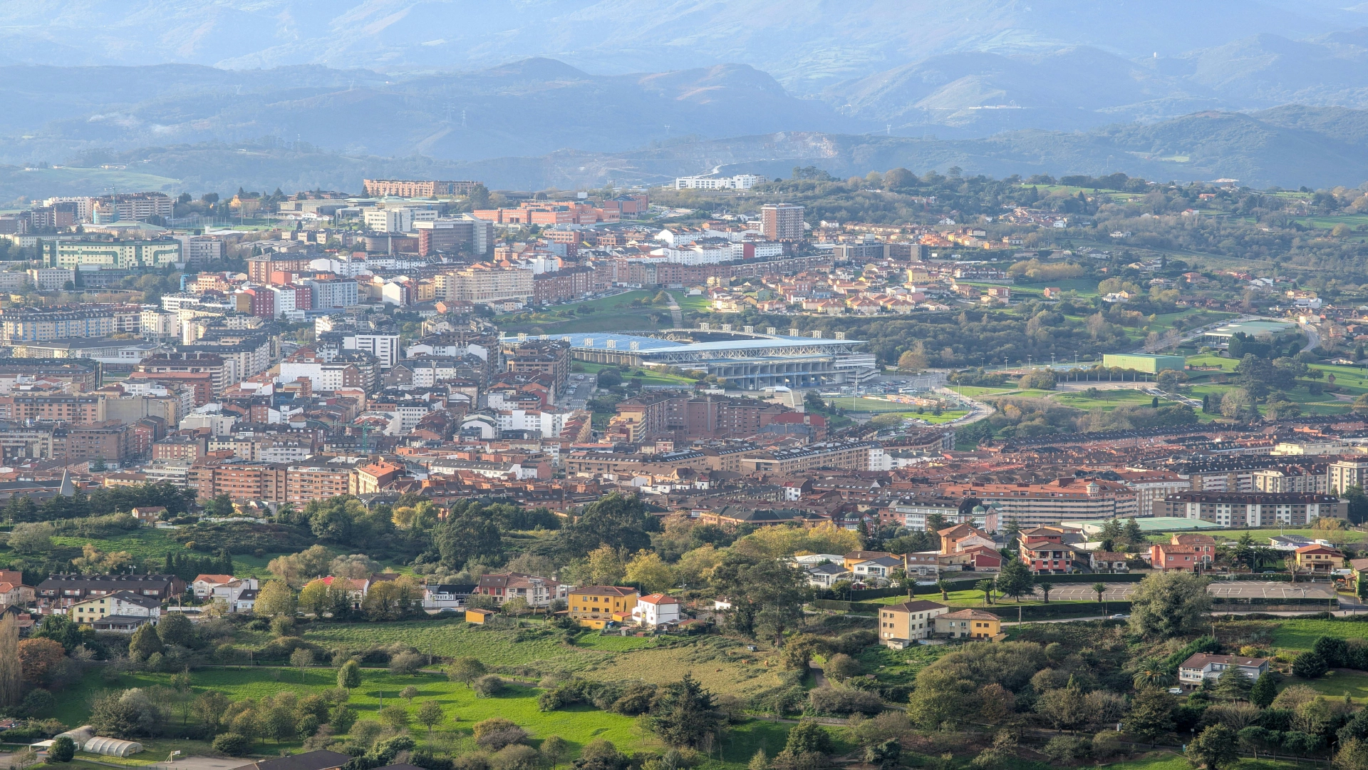 Panor&aacute;mica de ciudad y valle con monta&ntilde;as, campos y un puente ferroviario