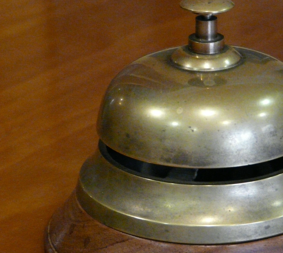 Timbre met&aacute;lico de conserje con bot&oacute;n superior sobre fondo color marr&oacute;n