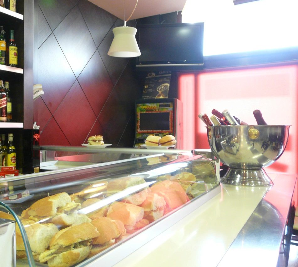 Vitrina con bocadillos, trofeo met&aacute;lico y barra de bar iluminada