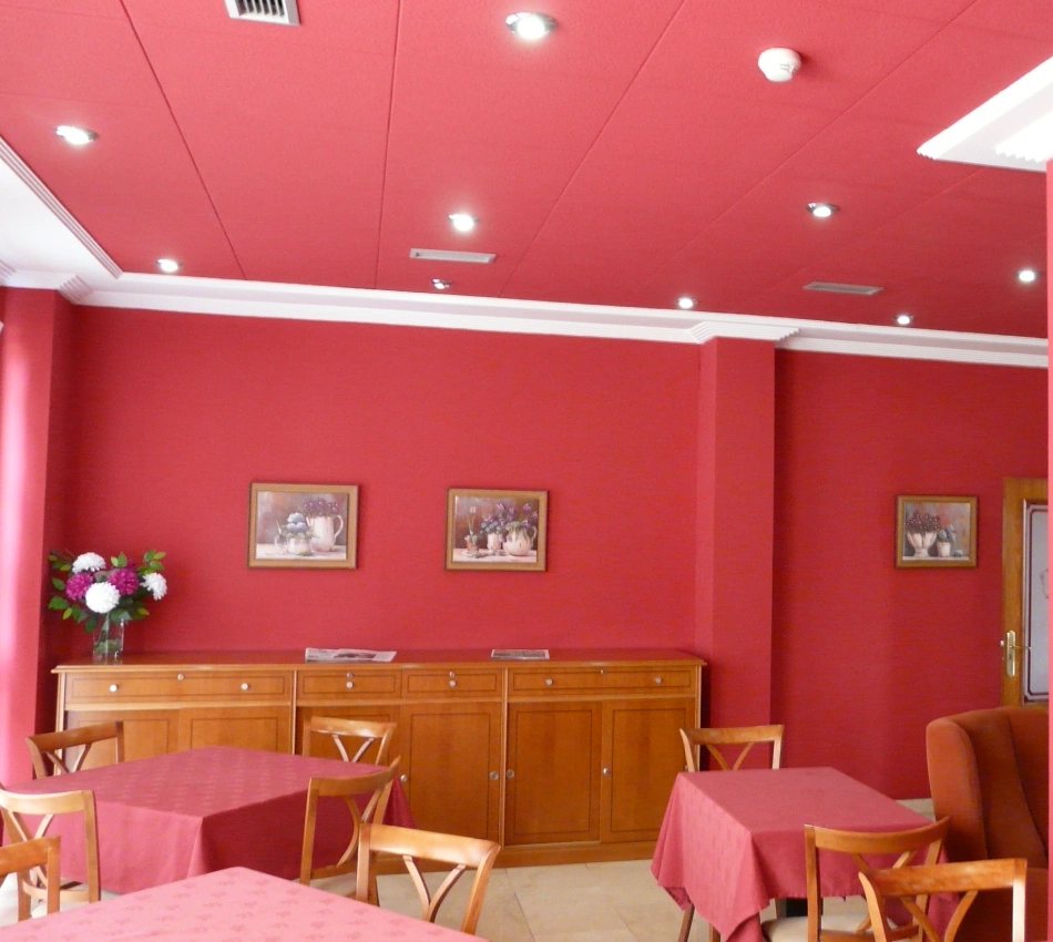Sala interior con paredes rojas, mesa con mantel rosa y luces en el techo