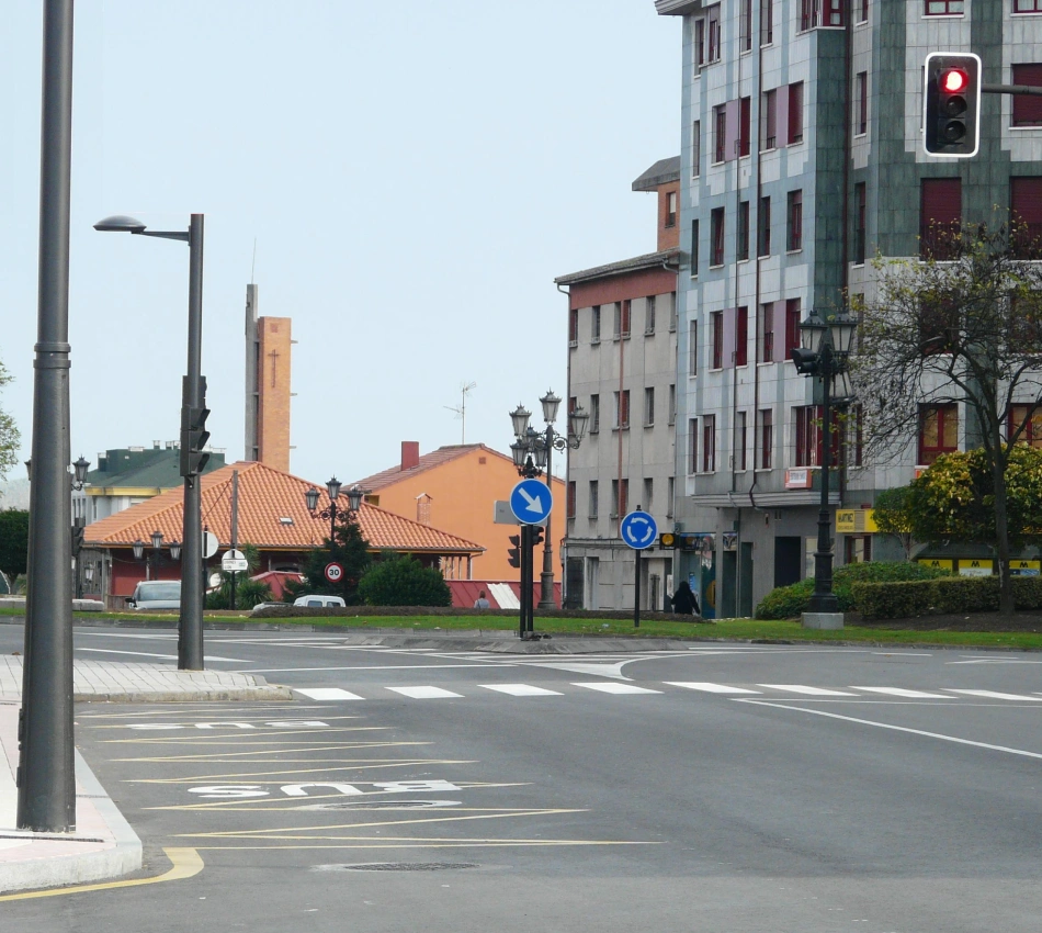 Cruce urbano con sem&aacute;foro en rojo y edificios al fondo, calle despejada