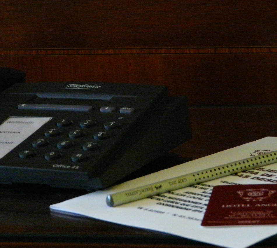 Calculadora y papeles sobre un escritorio, con l&aacute;piz y hoja parcialmente visible
