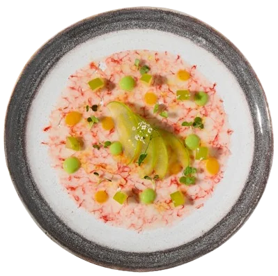 Plato de crema con palta y guisantes, decorado con jam&oacute;n y vegetales