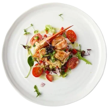 Plato de ensalada con pollo, tomate cherry y hojas verdes.