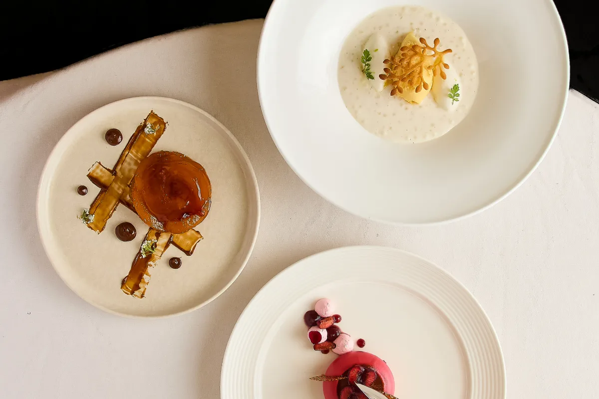 Tres platos con sopas cremosas y guarniciones, servidos sobre mesa blanca