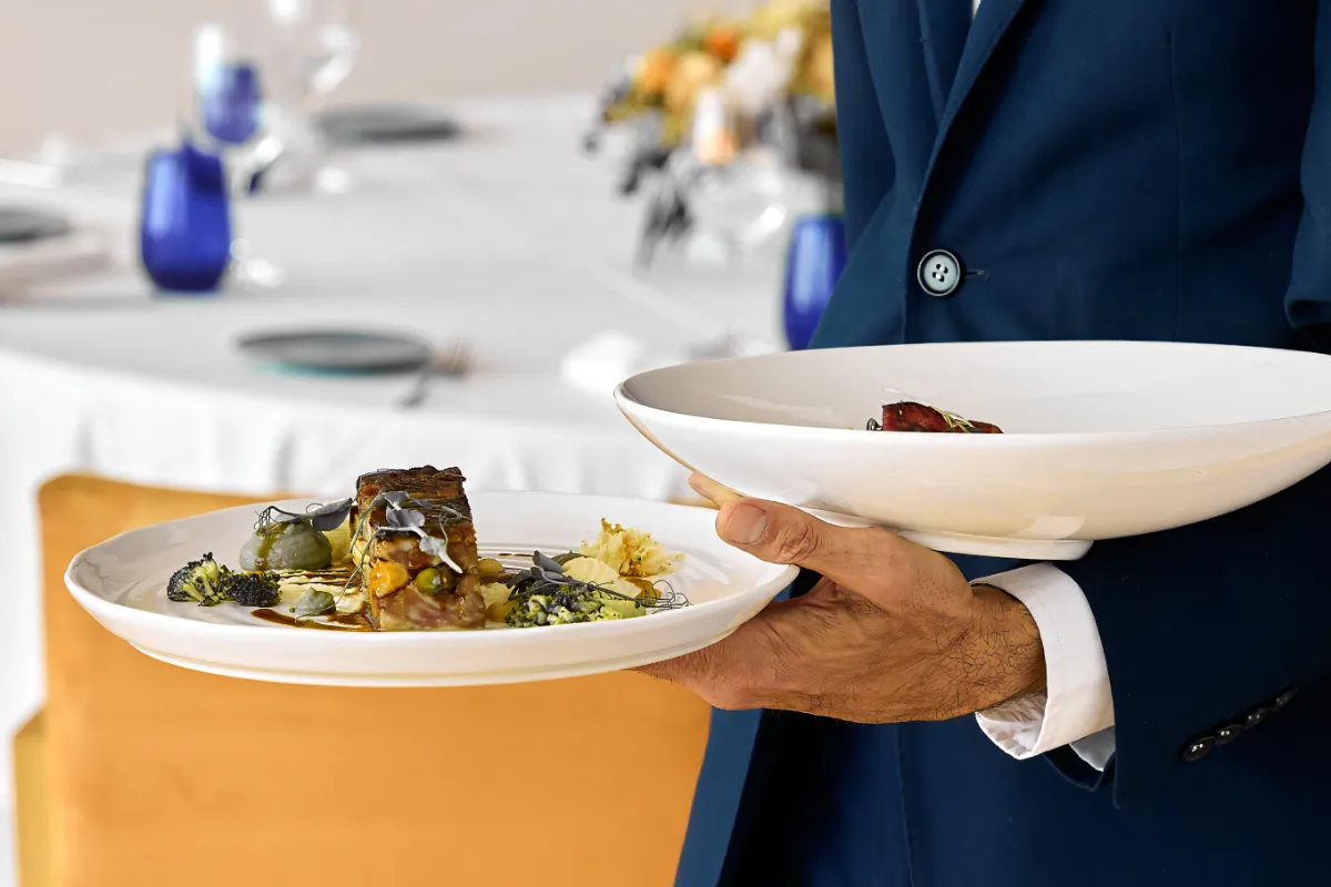 Chef sostiene un plato con comida gourmet en un banquete.