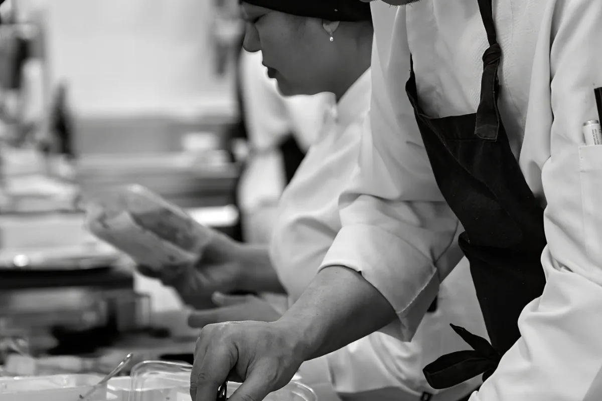 Foto en blanco y negro de un chef preparando alimentos en cocina.