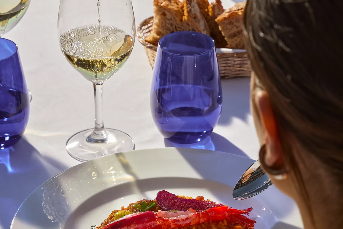 Vino blanco y azul con cena servida; persona a la derecha y pan en cesta