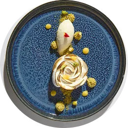 Plato azul con adorno de crema dorada y aves decorativas.