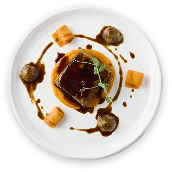 Plato de carne con salsa y cubos de queso sobre cama blanca