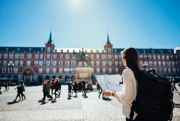 Estudiante con mochila observa un mapa en un campus con edificios rojos