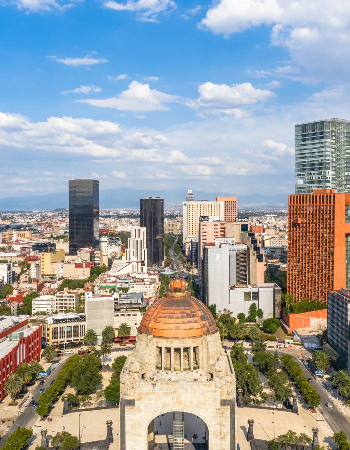 Ciudad con c&uacute;pula y edificios modernos bajo un cielo azul con nubes.