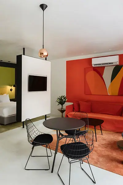 Modern living room corner with red sofa, pendant lamp, and small dining set
