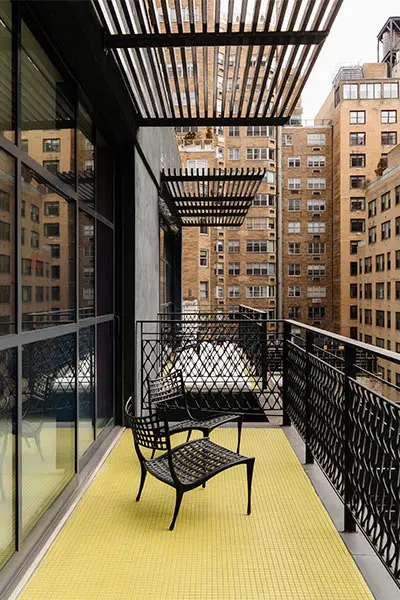 Balcony with railing, two chairs, and view of tall apartment buildings