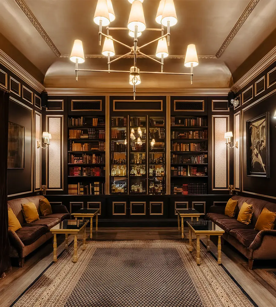 Luxury library lounge with dark wood bookshelves, chandeliers, and sofas