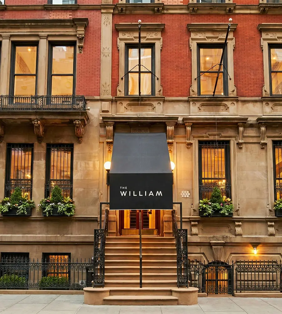 Entrance of The William hotel with stairs and marquee sign on a red-brick building